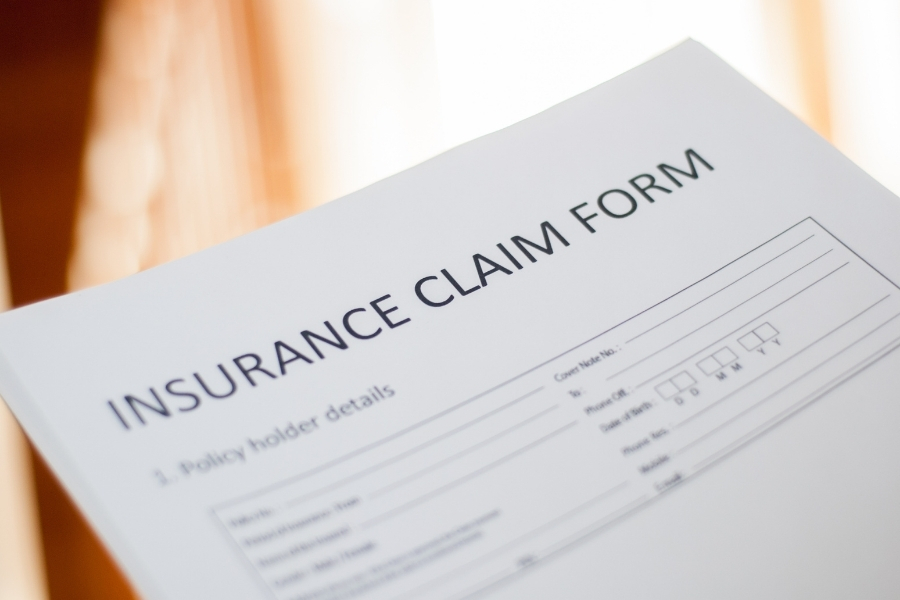 Homeowner reviewing an insurance claim and deductible paperwork at a kitchen table
