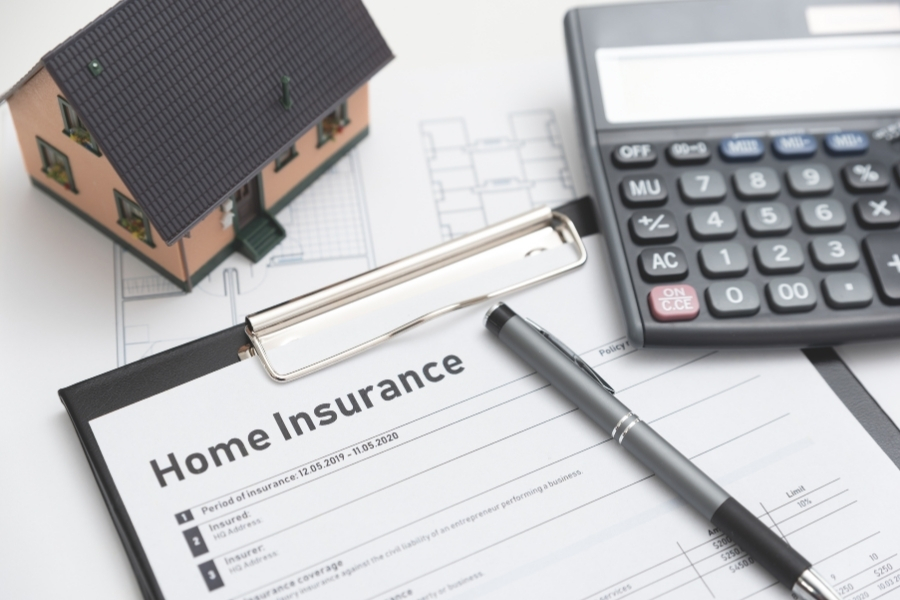 Homeowner reviewing a homeowners insurance policy and claim paperwork at a kitchen table